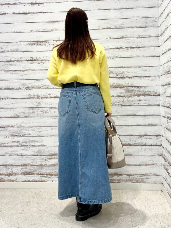 イエロー系のニット/セーター、ホワイト系のTシャツ/カットソー、ブルー系のデニムスカートを着用したレディースの冬コーディネートの3枚目の写真