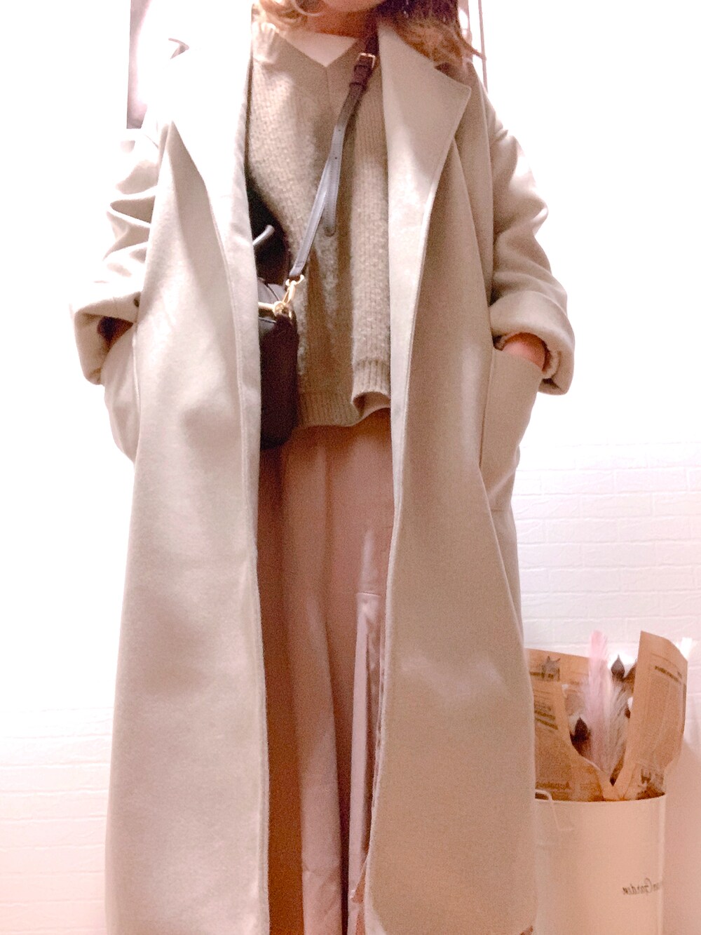 ブラウン系のショルダーバッグ、ピンク系のスカート、ブラウン系のベストを着用したレディースの冬コーディネートの2枚目の写真