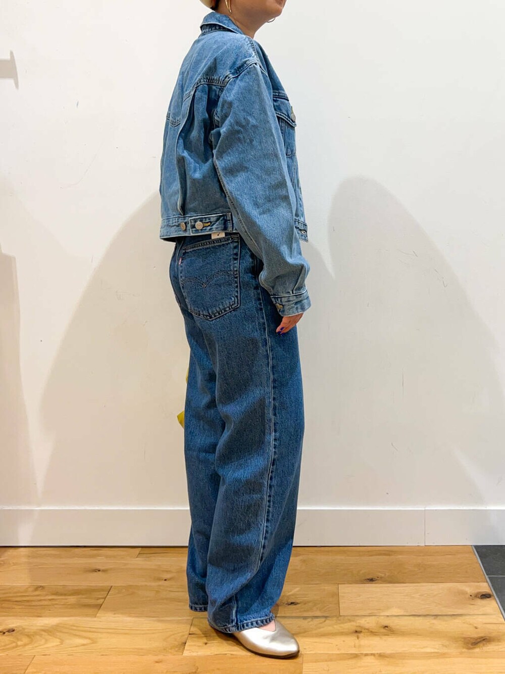 イエロー系のハンドバッグ、ブルー系のデニムパンツ、ブルー系のデニムジャケットを着用したレディースの夏コーディネートの4枚目の写真