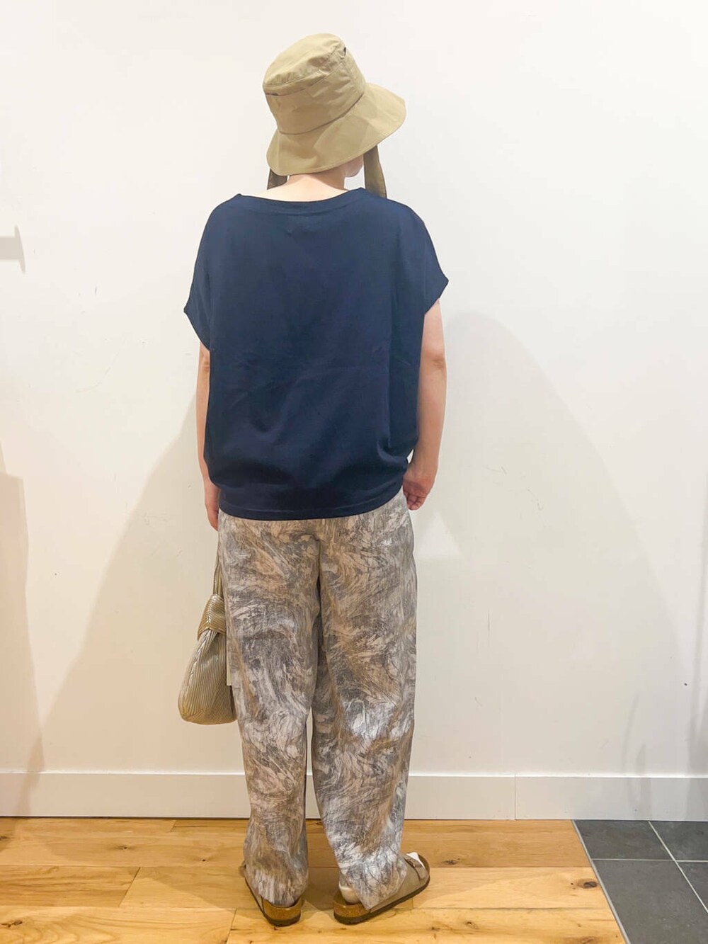 ブルー系のTシャツ/カットソー、ゴールド系のハンドバッグ、ベージュ系のサンダルを着用したレディースの夏コーディネートの3枚目の写真