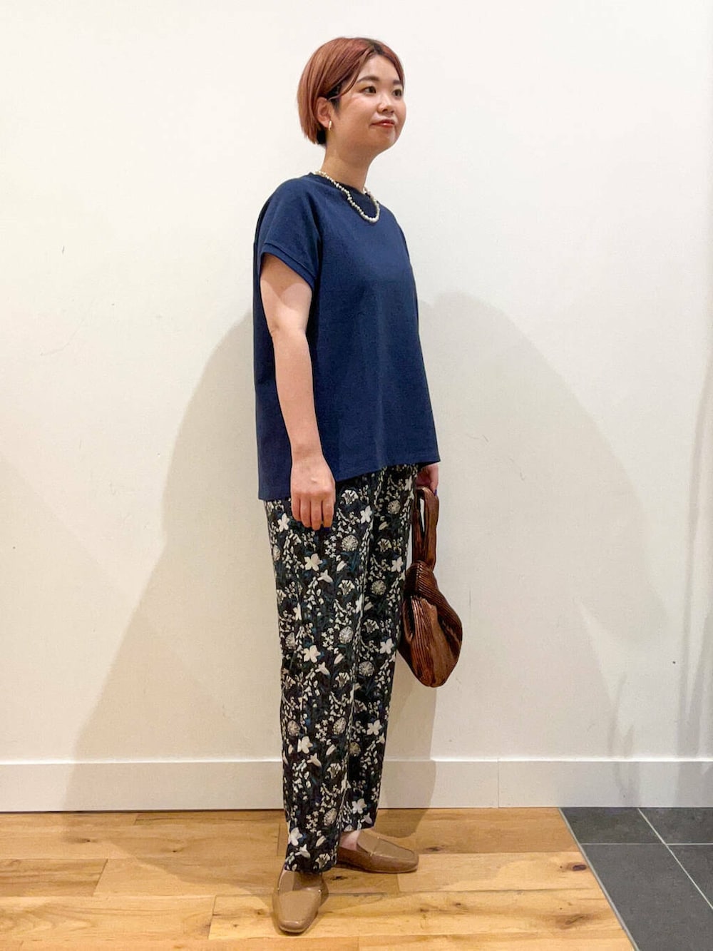 ベージュ系のローファー、ブラウン系のハンドバッグ、ブルー系のTシャツ/カットソーを着用したレディースの夏コーディネートの2枚目の写真