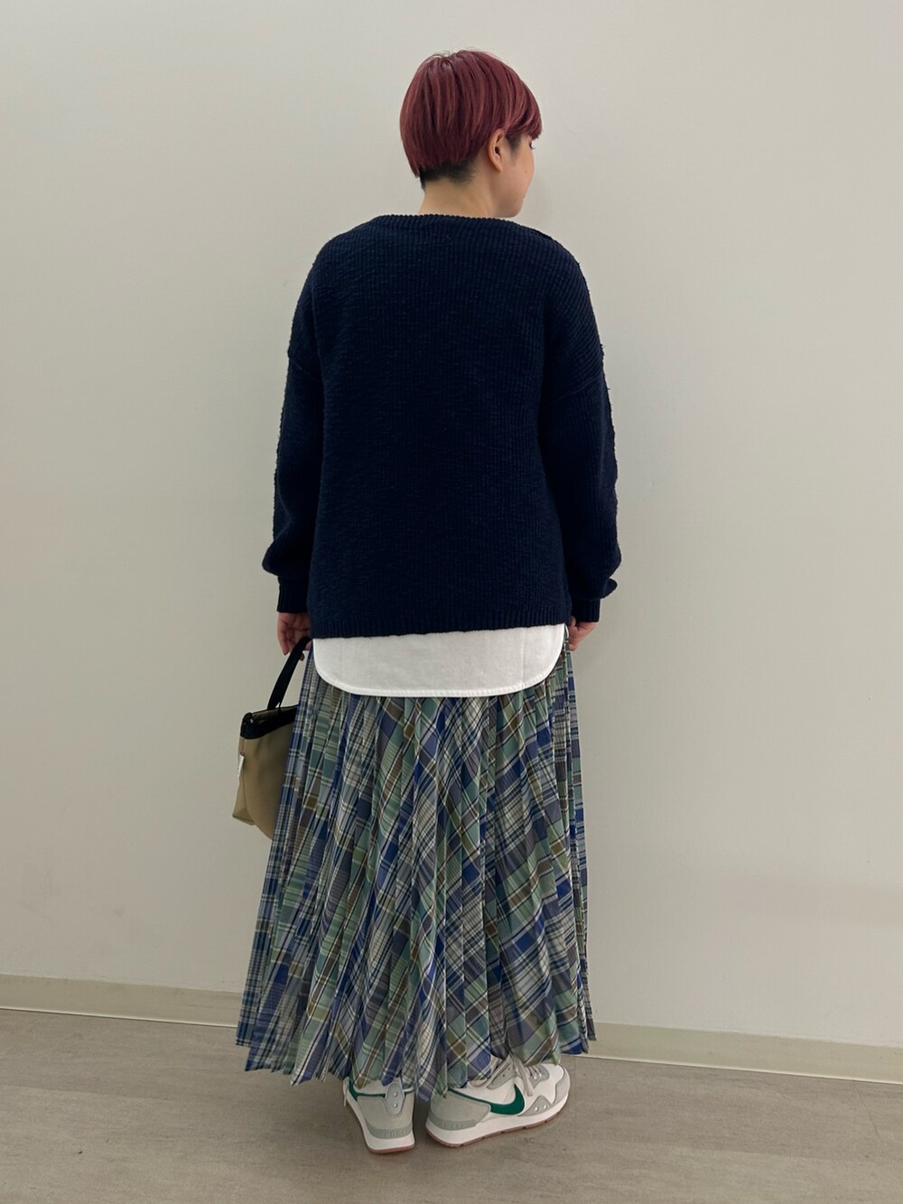 グリーン系のスカート、ベージュ系のショルダーバッグ、ベージュ系のスニーカーを着用したレディースの春コーディネートの2枚目の写真