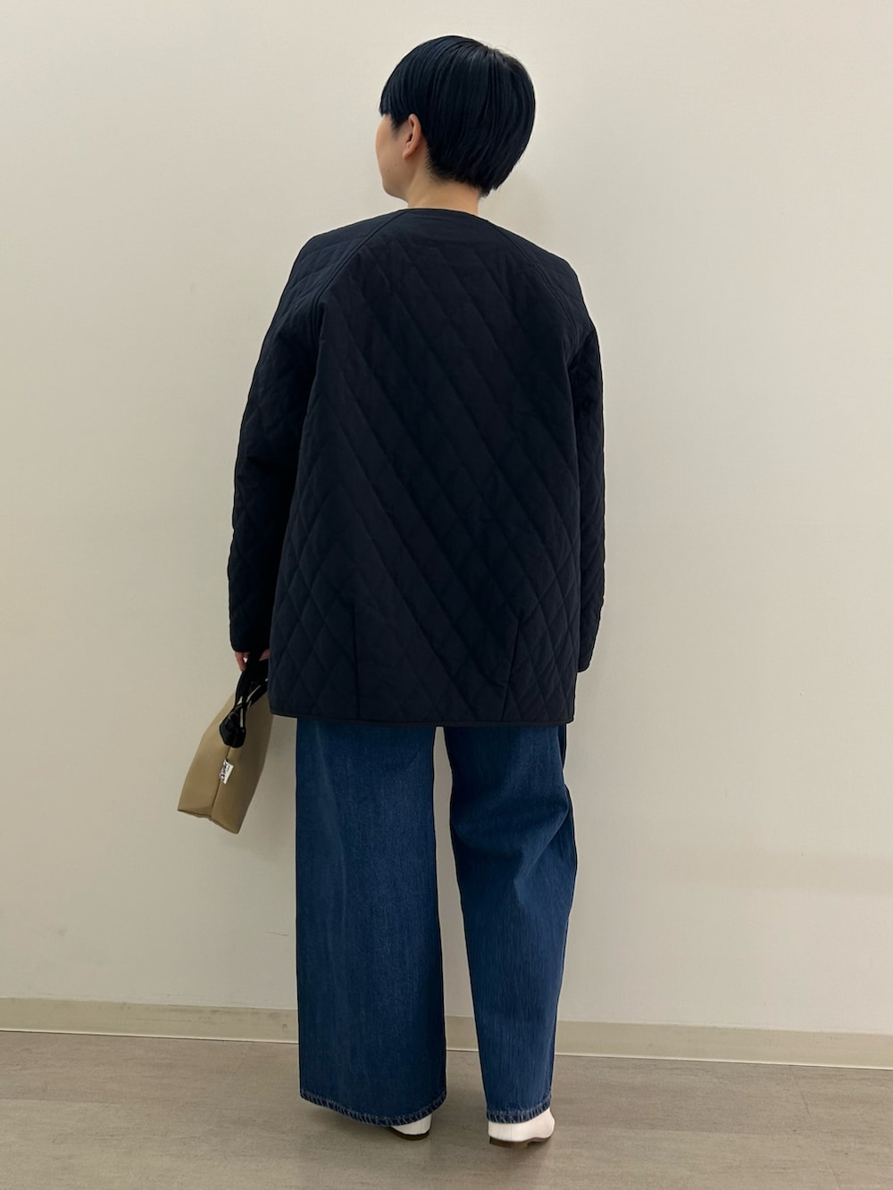 ホワイト系のパンプス、ブルー系のダウンジャケット/コート、ベージュ系のショルダーバッグを着用したレディースの冬コーディネートの2枚目の写真