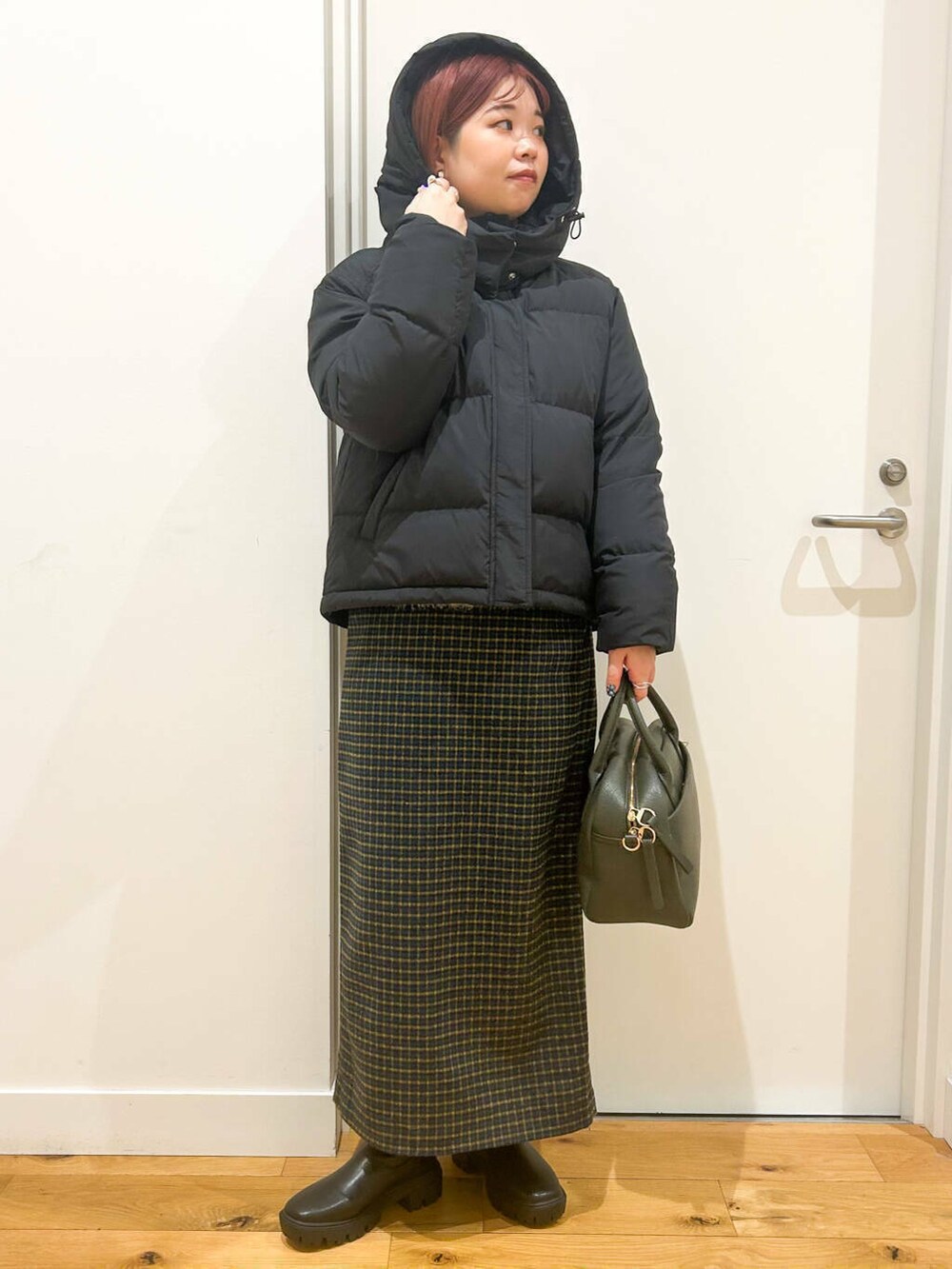 グリーン系のボストンバッグ、ブラック系のブーツ、レッド系のTシャツ/カットソーを着用したレディースの冬コーディネートの3枚目の写真