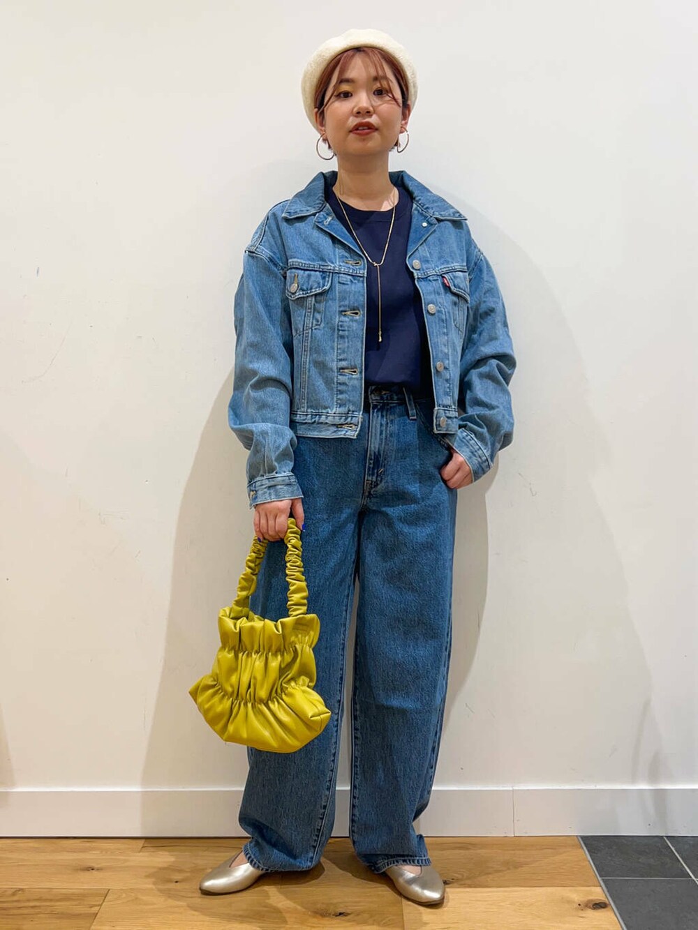 イエロー系のハンドバッグ、ブルー系のデニムパンツ、ブルー系のデニムジャケットを着用したレディースの夏コーディネートの2枚目の写真