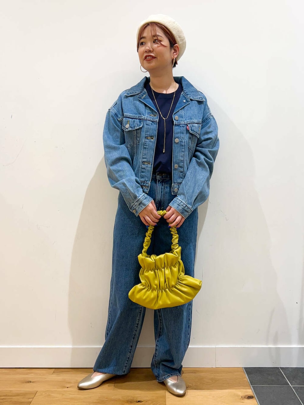 イエロー系のハンドバッグ、ブルー系のデニムパンツ、ブルー系のデニムジャケットを着用したレディースの夏コーディネートの3枚目の写真