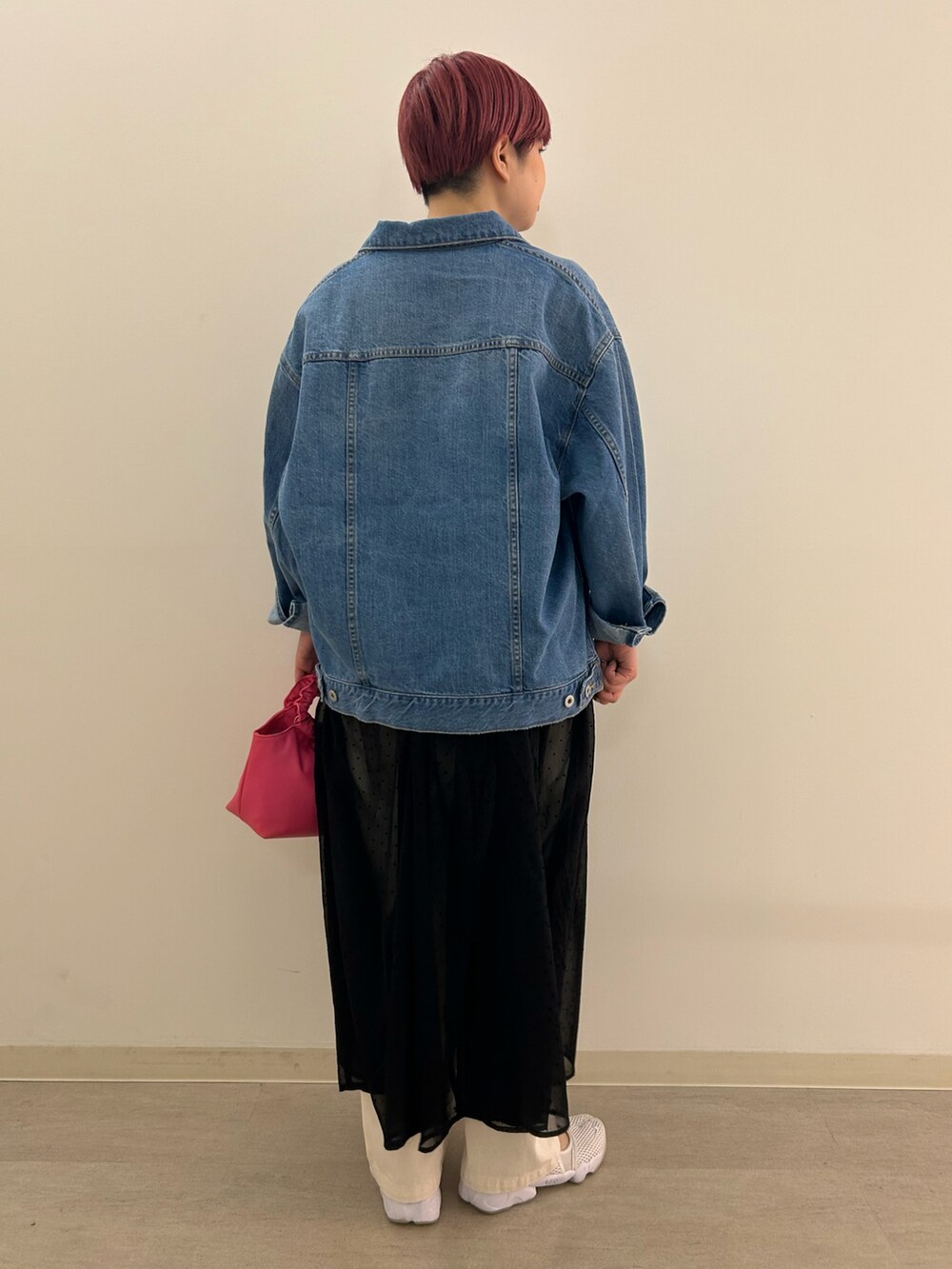 ブルー系のデニムジャケット、ピンク系のショルダーバッグ、ベージュ系のデニムパンツを着用したレディースの春コーディネートの2枚目の写真