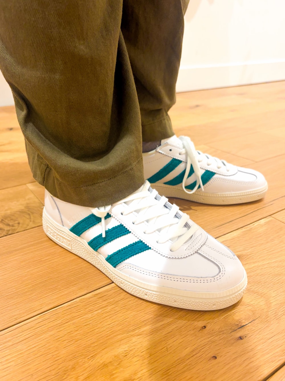 ホワイト系のスニーカー、グリーン系のサロペット/オーバーオール、ブラック系のショルダーバッグを着用したレディースの春コーディネートの5枚目の写真