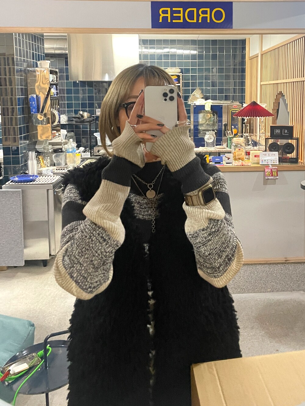 ホワイト系のスカート、ブラック系のベスト、ブラック系のニット/セーターを着用したレディースの春コーディネートの2枚目の写真