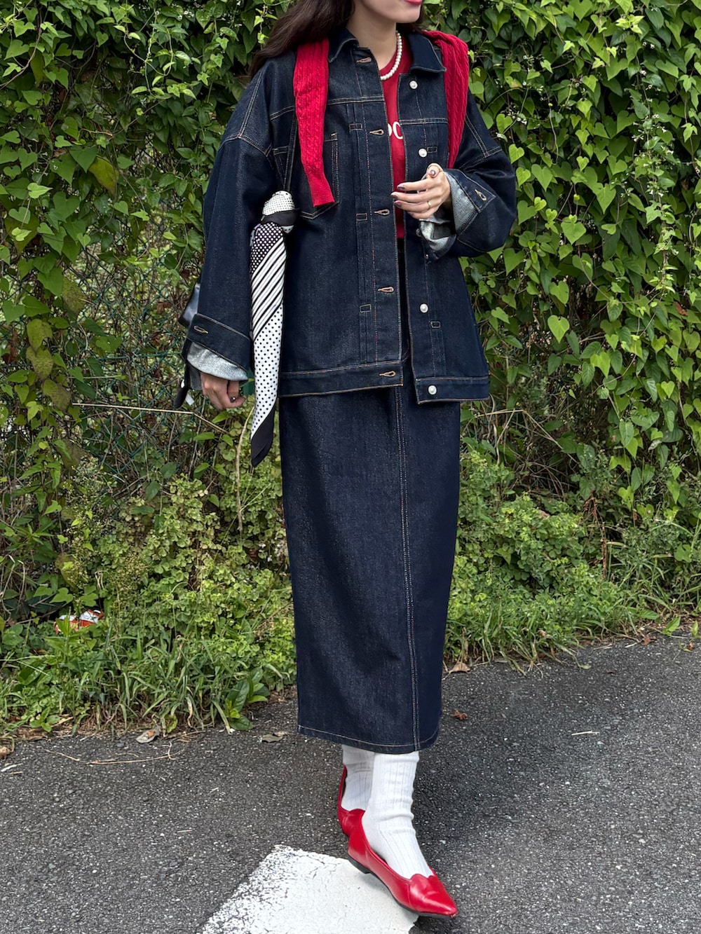 ブルー系のデニムジャケット、ブルー系のデニムスカート、レッド系のパンプスを着用したレディースの秋コーディネートの2枚目の写真