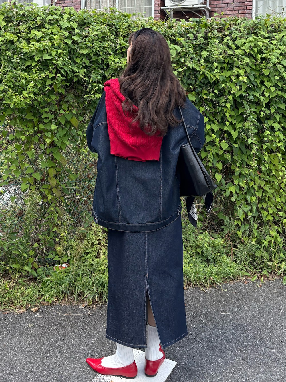 ブルー系のデニムジャケット、ブルー系のデニムスカート、レッド系のパンプスを着用したレディースの秋コーディネートの3枚目の写真