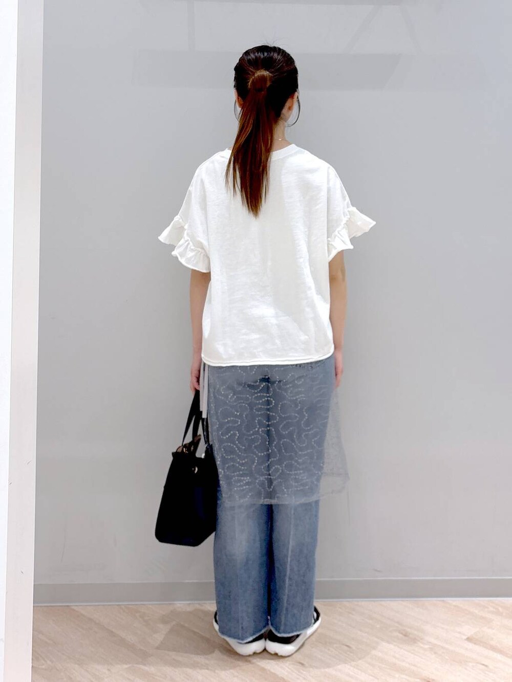 ブルー系のデニムパンツ、ホワイト系のショルダーバッグ、ブラック系のサンダルを着用したレディースの春コーディネートの4枚目の写真