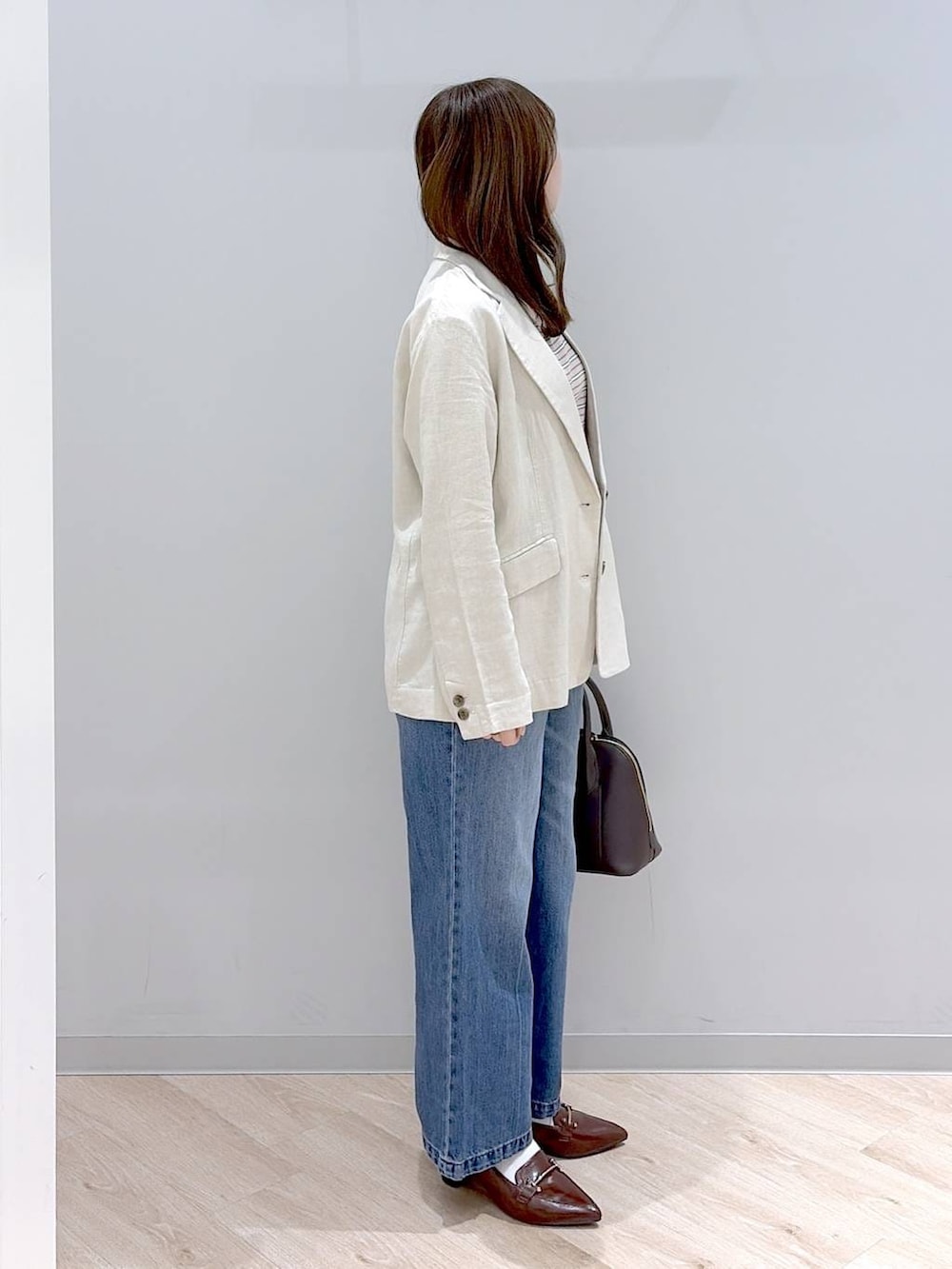 ブルー系のデニムパンツ、ベージュ系のテーラードジャケット、ベージュ系のタンクトップを着用したレディースの春コーディネートの3枚目の写真