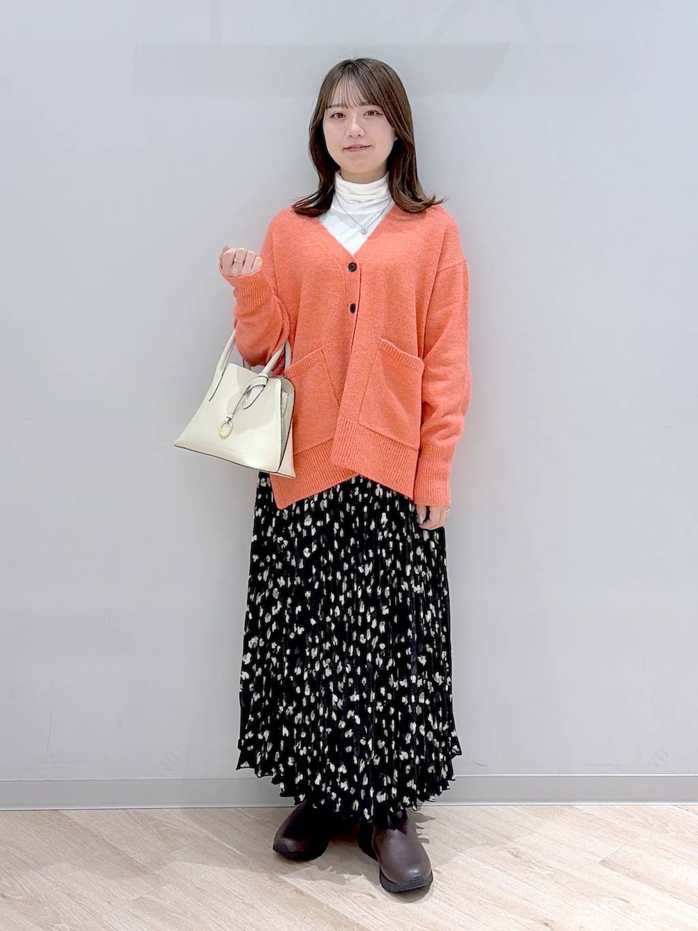 ホワイト系のショルダーバッグ、ピンク系のカーディガン/ボレロ、ホワイト系のTシャツ/カットソーを着用したレディースの冬コーディネートの2枚目の写真