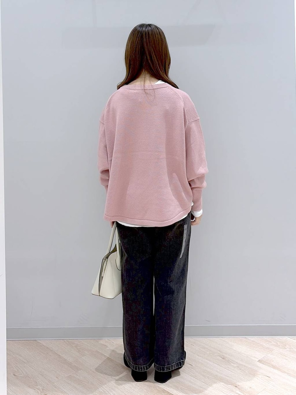 ホワイト系のショルダーバッグ、ピンク系のニット/セーター、ブラック系のデニムパンツを着用したレディースの冬コーディネートの4枚目の写真