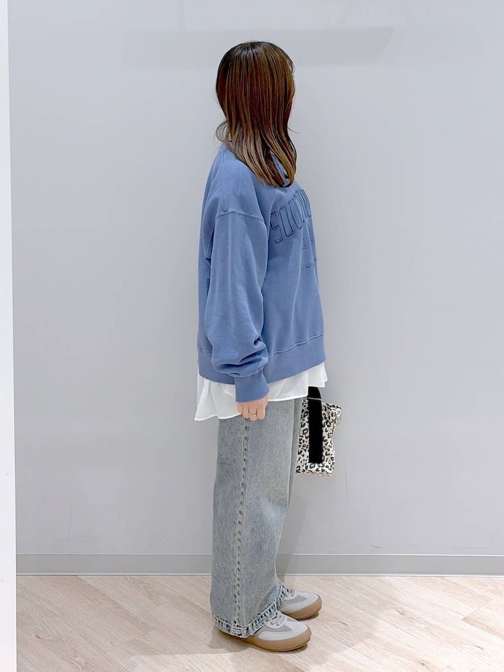 グレー系のスニーカー、ブラウン系のトートバッグ、ブルー系のデニムパンツを着用したレディースの冬コーディネートの3枚目の写真