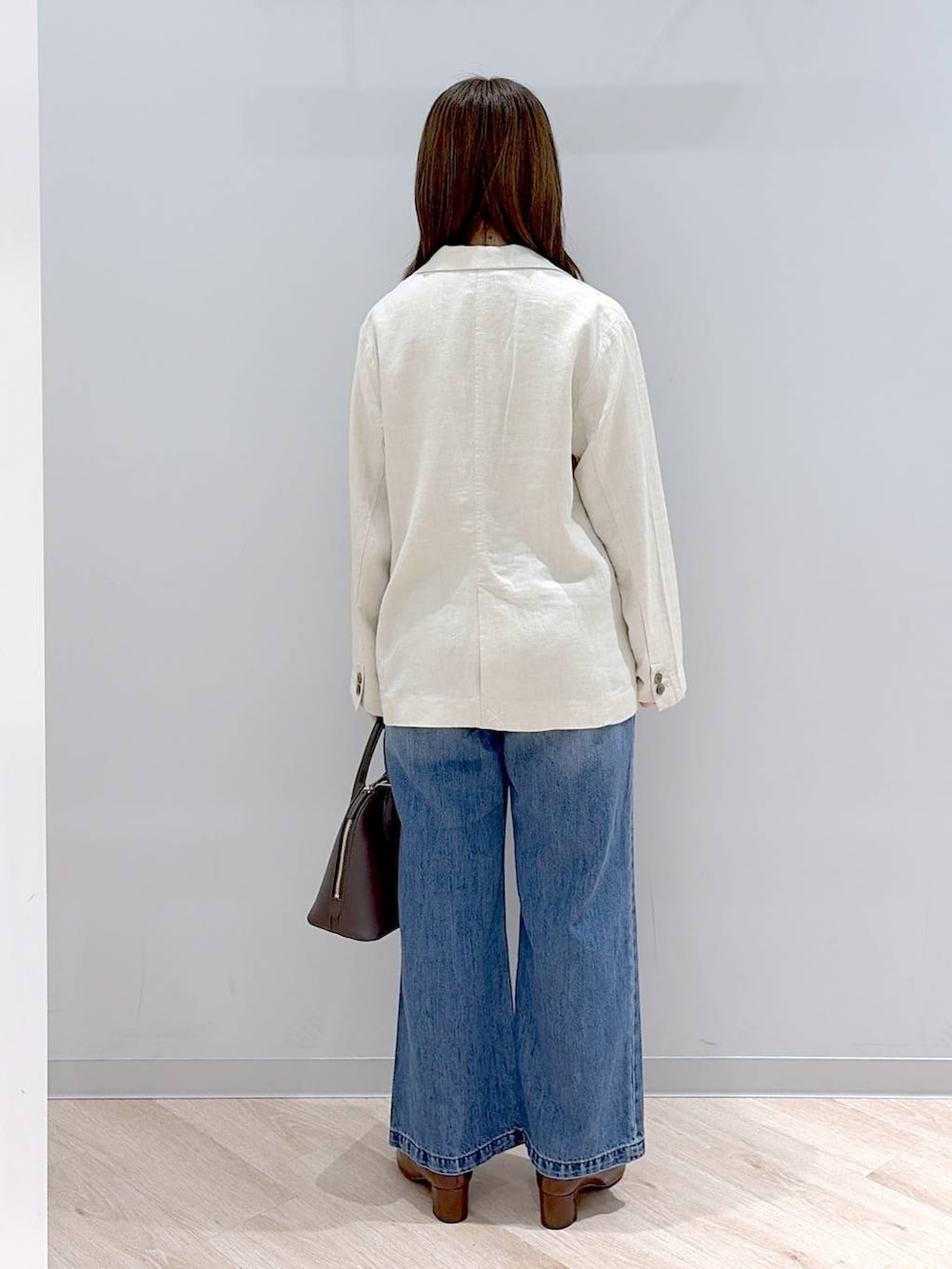 ブルー系のデニムパンツ、ベージュ系のテーラードジャケット、ベージュ系のタンクトップを着用したレディースの春コーディネートの4枚目の写真