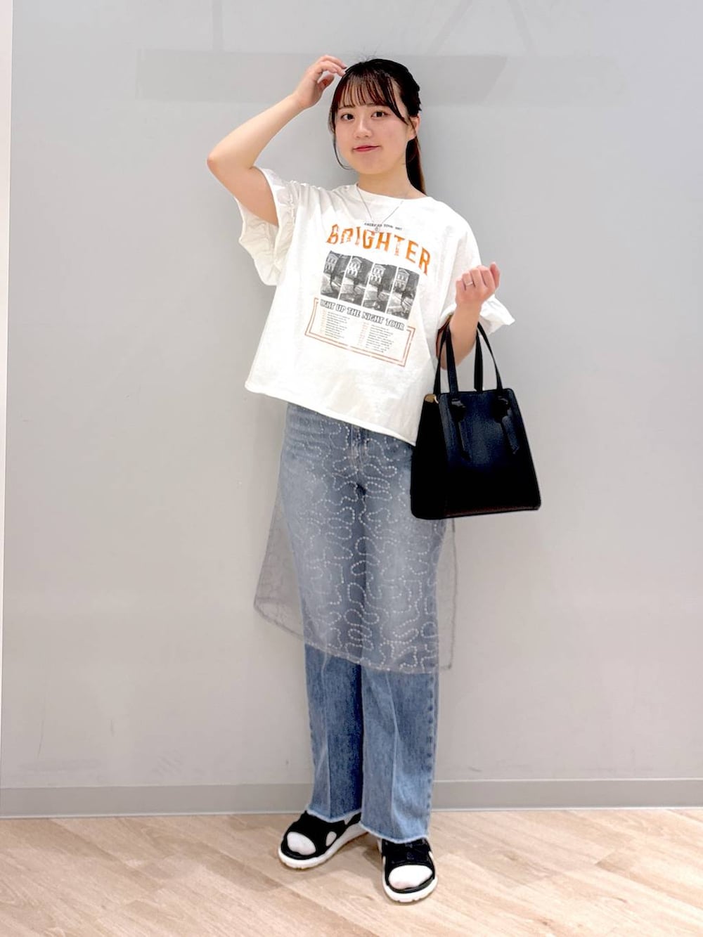 ブルー系のデニムパンツ、ホワイト系のショルダーバッグ、ブラック系のサンダルを着用したレディースの春コーディネートの2枚目の写真