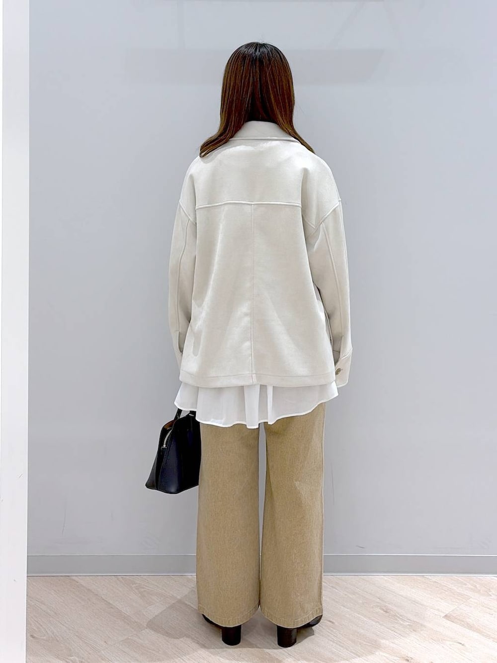 ブラック系のショルダーバッグ、ホワイト系のTシャツ/カットソー、ブルー系のニット/セーターを着用したレディースの冬コーディネートの4枚目の写真