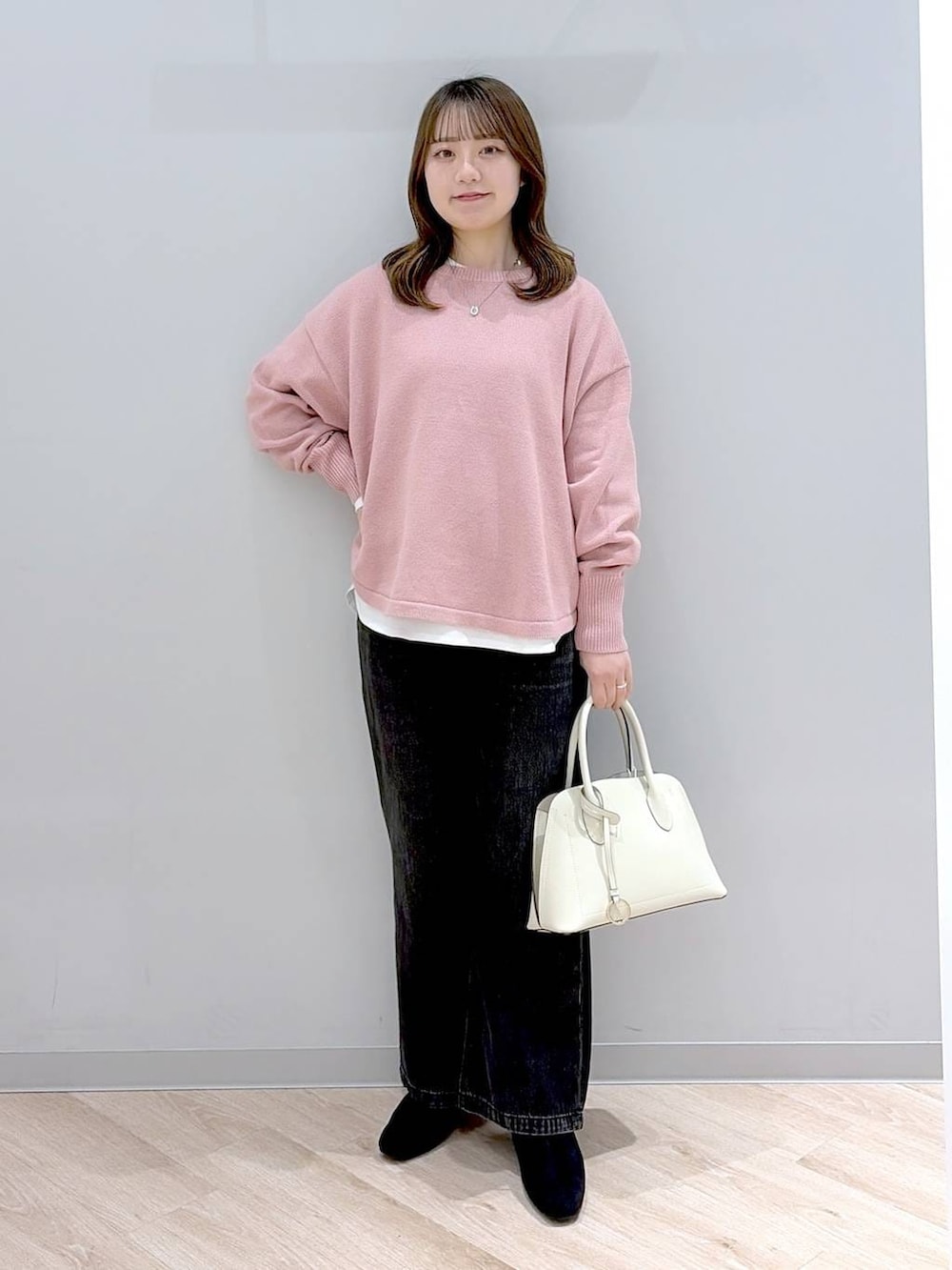 ホワイト系のショルダーバッグ、ピンク系のニット/セーター、ブラック系のデニムパンツを着用したレディースの冬コーディネートの2枚目の写真