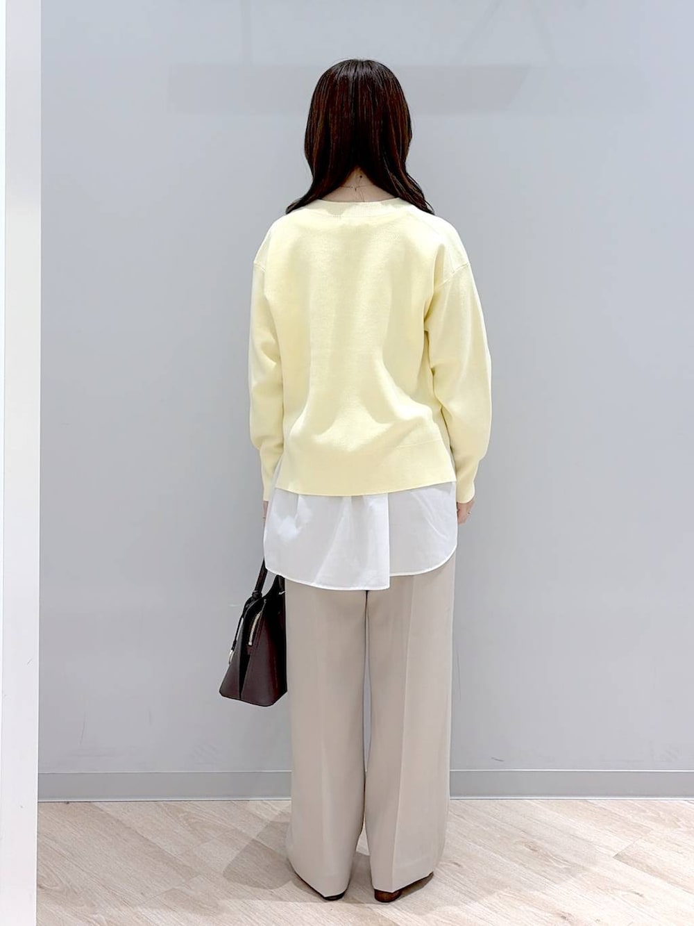 ブラウン系のショルダーバッグ、イエロー系のニット/セーター、ベージュ系のその他パンツを着用したレディースの春コーディネートの4枚目の写真