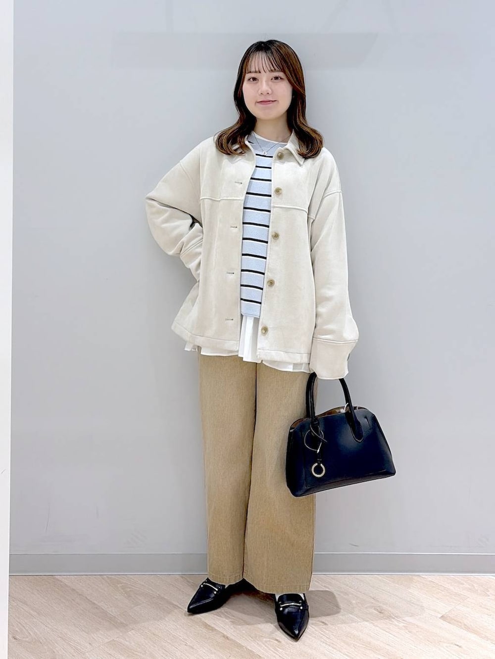 ブラック系のショルダーバッグ、ホワイト系のTシャツ/カットソー、ブルー系のニット/セーターを着用したレディースの冬コーディネートの2枚目の写真