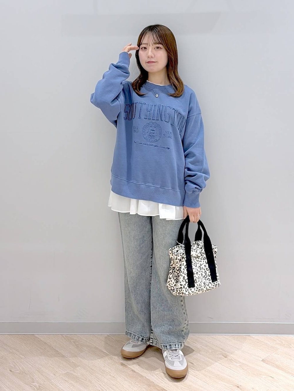 グレー系のスニーカー、ブラウン系のトートバッグ、ブルー系のデニムパンツを着用したレディースの冬コーディネートの2枚目の写真