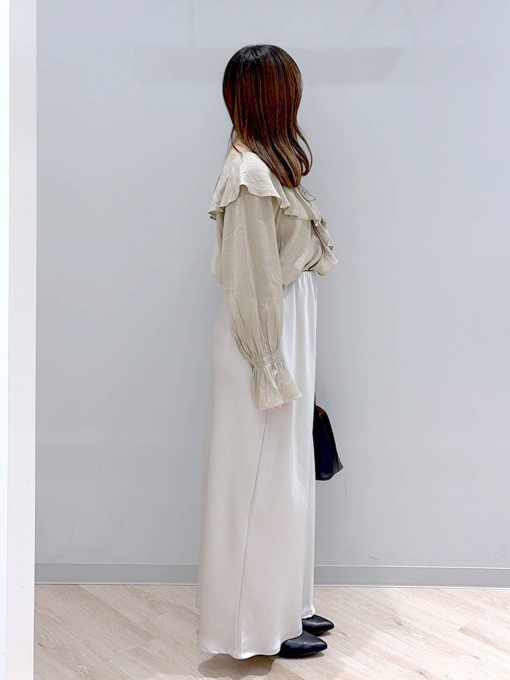 ブラック系のショルダーバッグ、ブラック系のパンプス、グレー系のスカートを着用したレディースの春コーディネートの3枚目の写真