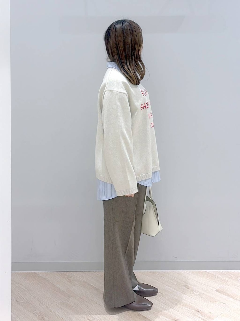 ホワイト系のショルダーバッグ、ブルー系のシャツ/ブラウス、ベージュ系のニット/セーターを着用したレディースの冬コーディネートの3枚目の写真