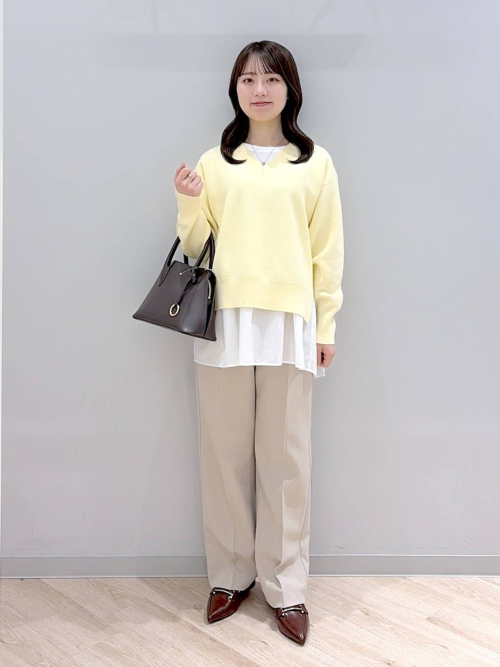 ブラウン系のショルダーバッグ、イエロー系のニット/セーター、ベージュ系のその他パンツを着用したレディースの春コーディネートの2枚目の写真