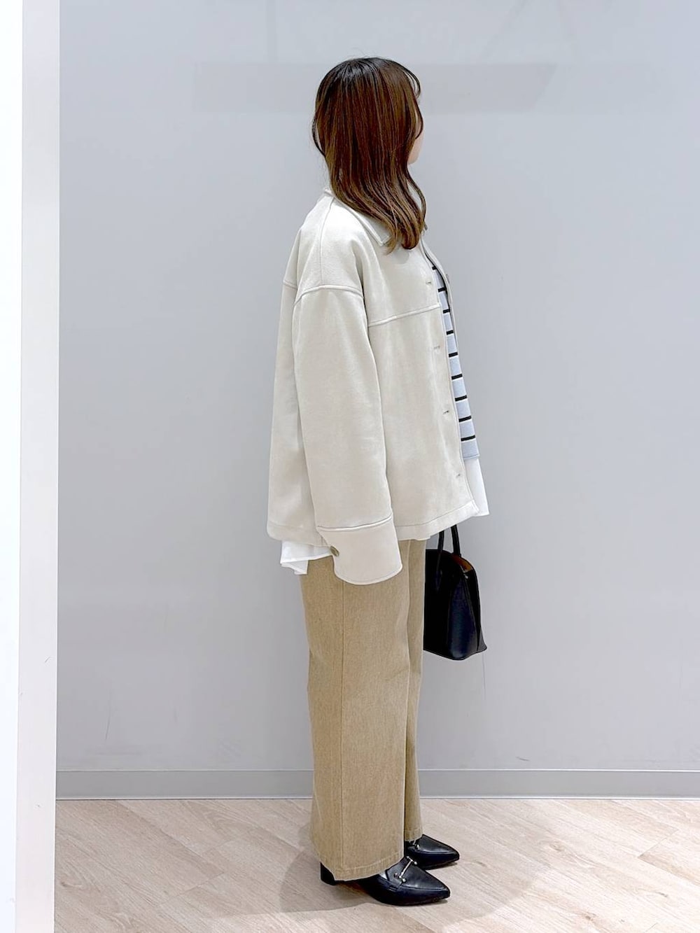 ブラック系のショルダーバッグ、ホワイト系のTシャツ/カットソー、ブルー系のニット/セーターを着用したレディースの冬コーディネートの3枚目の写真