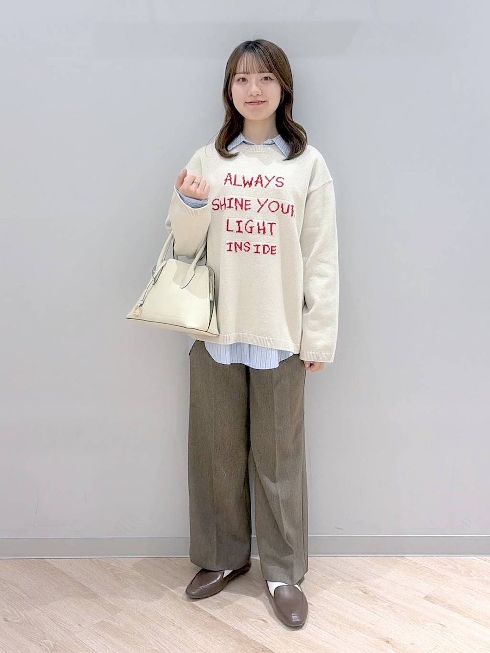 ホワイト系のショルダーバッグ、ブルー系のシャツ/ブラウス、ベージュ系のニット/セーターを着用したレディースの冬コーディネートの2枚目の写真