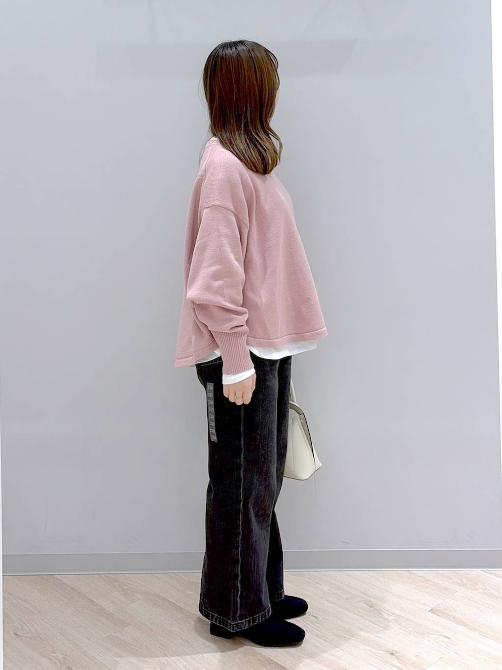 ホワイト系のショルダーバッグ、ピンク系のニット/セーター、ブラック系のデニムパンツを着用したレディースの冬コーディネートの3枚目の写真