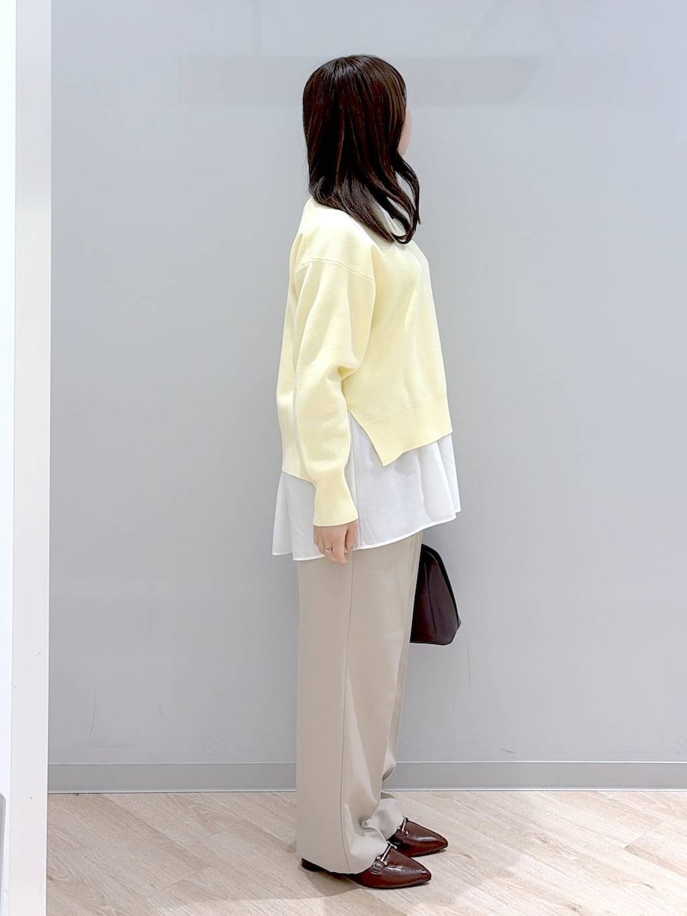 ブラウン系のショルダーバッグ、イエロー系のニット/セーター、ベージュ系のその他パンツを着用したレディースの春コーディネートの3枚目の写真