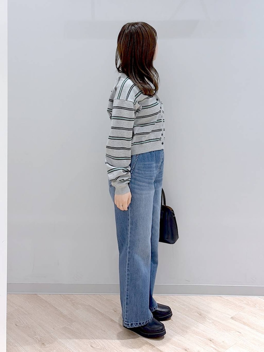 ブラック系のローファー、ブラック系のショルダーバッグ、ブルー系のデニムパンツを着用したレディースの春コーディネートの3枚目の写真