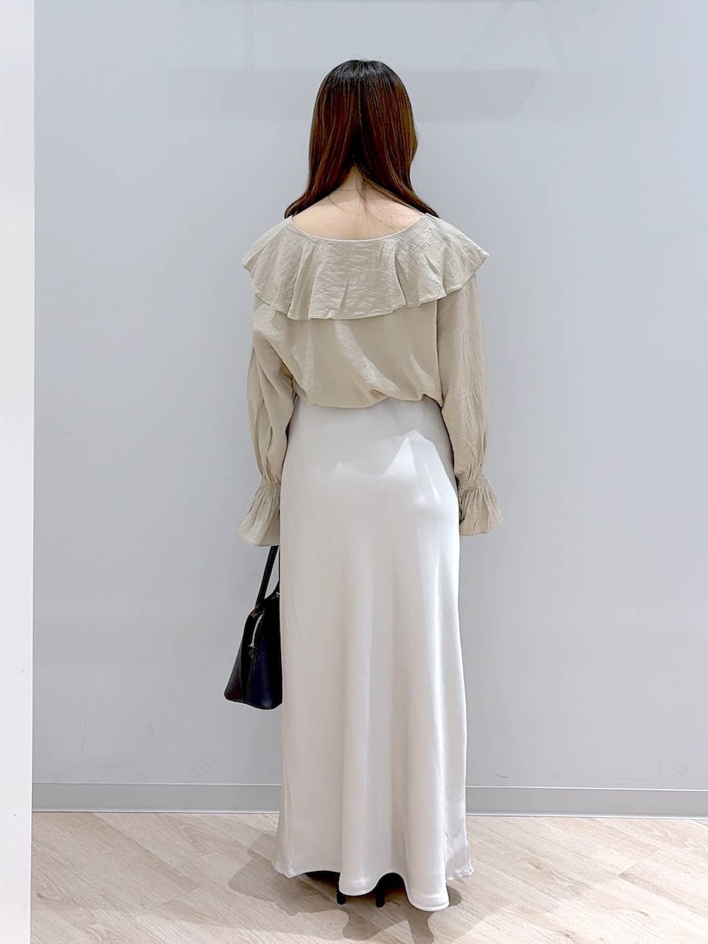 ブラック系のショルダーバッグ、ブラック系のパンプス、グレー系のスカートを着用したレディースの春コーディネートの4枚目の写真