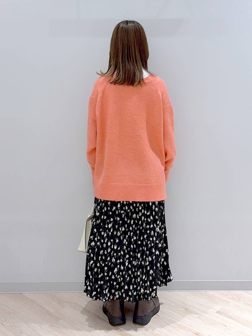 ホワイト系のショルダーバッグ、ピンク系のカーディガン/ボレロ、ホワイト系のTシャツ/カットソーを着用したレディースの冬コーディネートの4枚目の写真