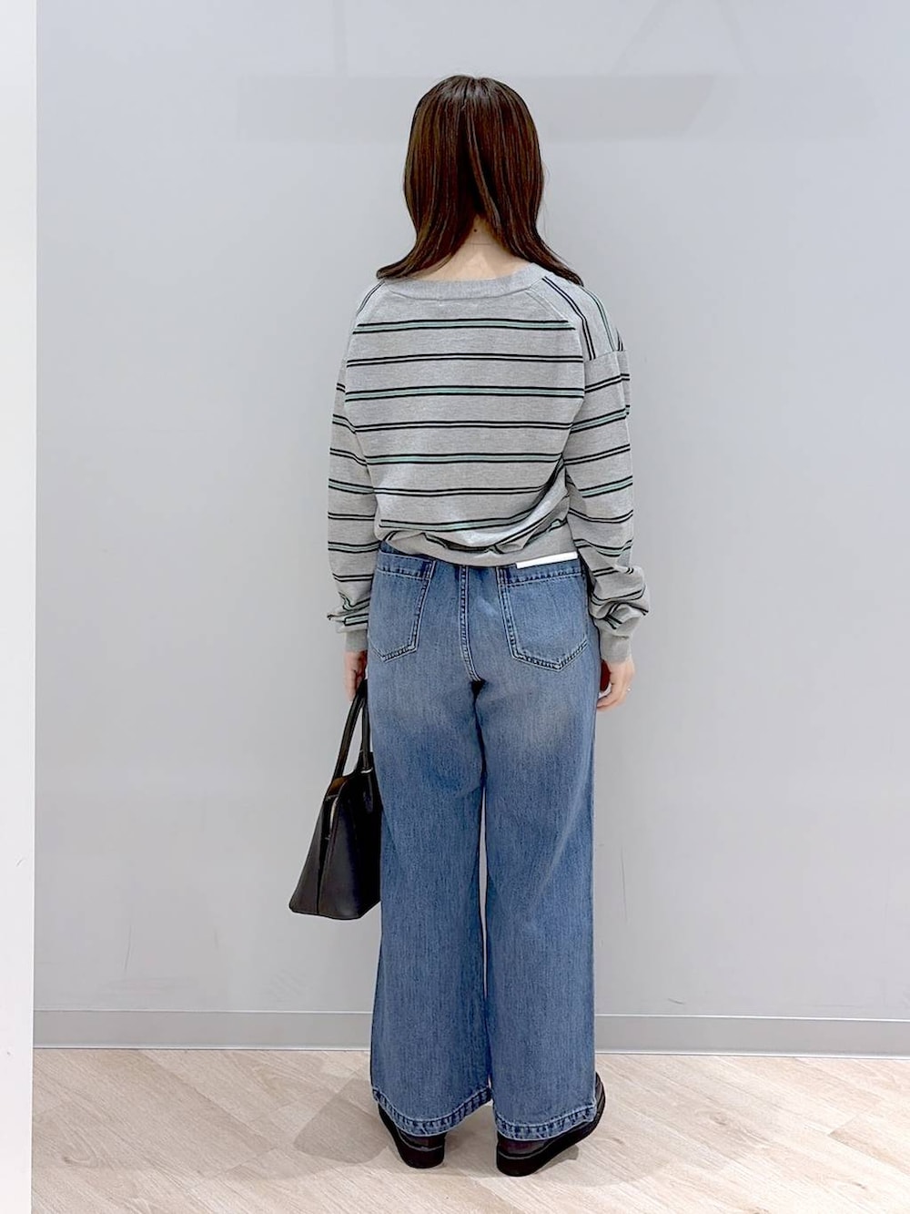 ブラック系のローファー、ブラック系のショルダーバッグ、ブルー系のデニムパンツを着用したレディースの春コーディネートの4枚目の写真