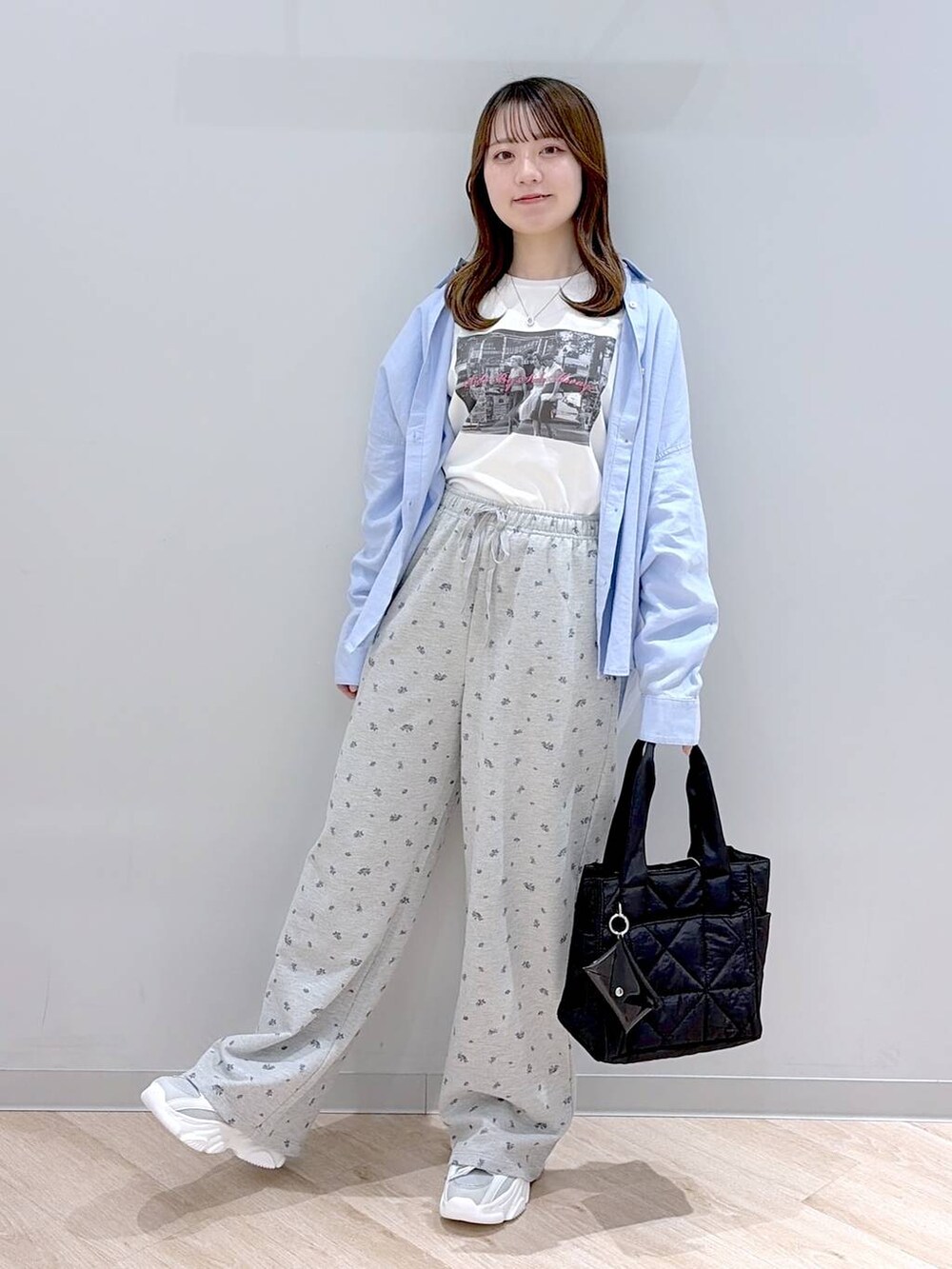 ブラック系のトートバッグ、ブルー系のシャツ/ブラウス、ホワイト系のTシャツ/カットソーを着用したレディースの春コーディネートの2枚目の写真