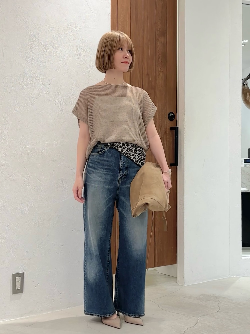 ベージュ系のニット/セーター、ブルー系のデニムパンツ、グリーン系のショルダーバッグを着用したレディースの夏コーディネートの3枚目の写真