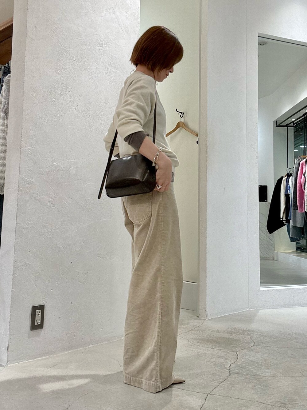 ホワイト系のニット/セーター、グレー系のTシャツ/カットソー、ブラウン系のショルダーバッグを着用したレディースの夏コーディネートの3枚目の写真