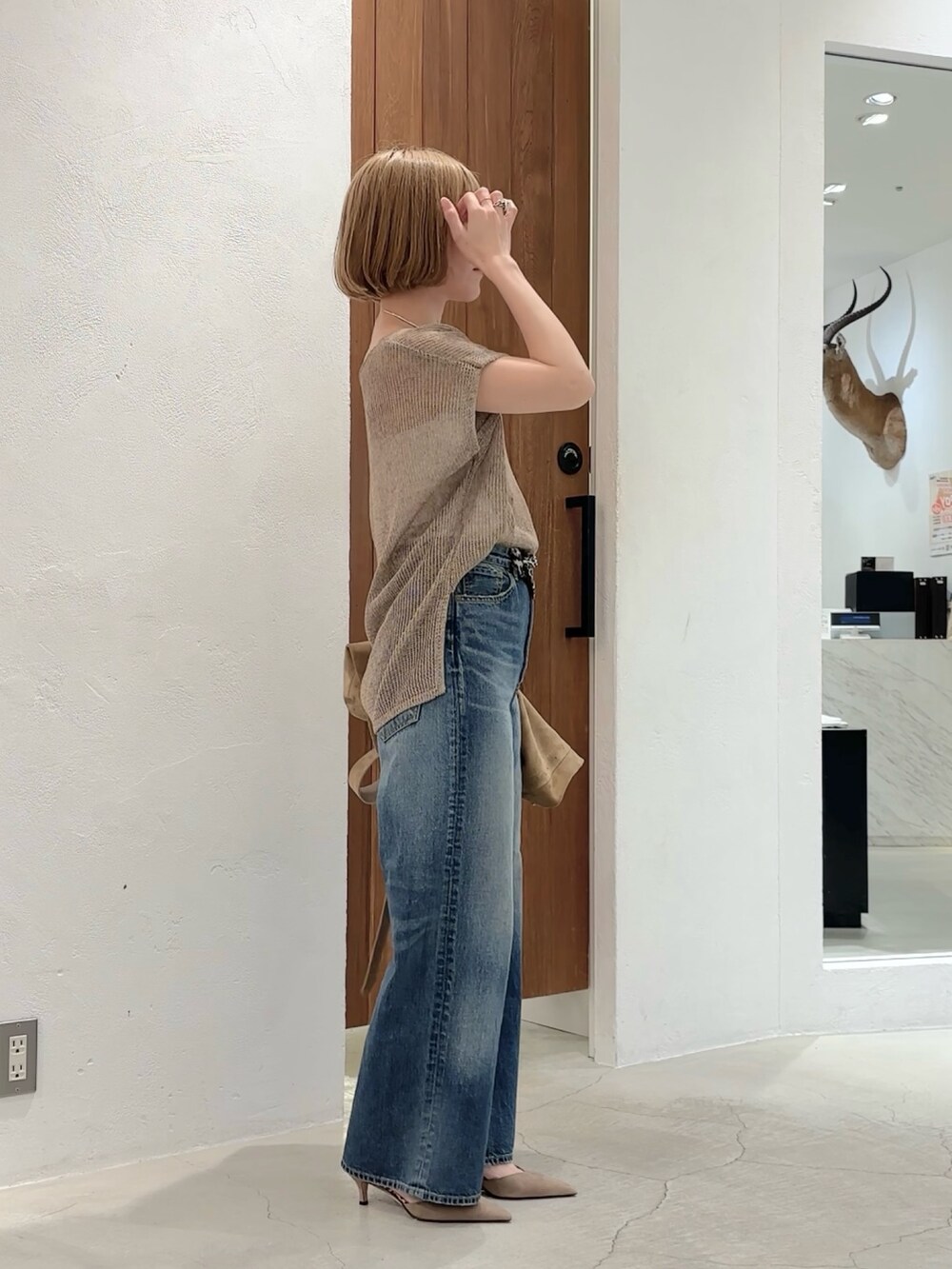 ベージュ系のニット/セーター、ブルー系のデニムパンツ、グリーン系のショルダーバッグを着用したレディースの夏コーディネートの2枚目の写真
