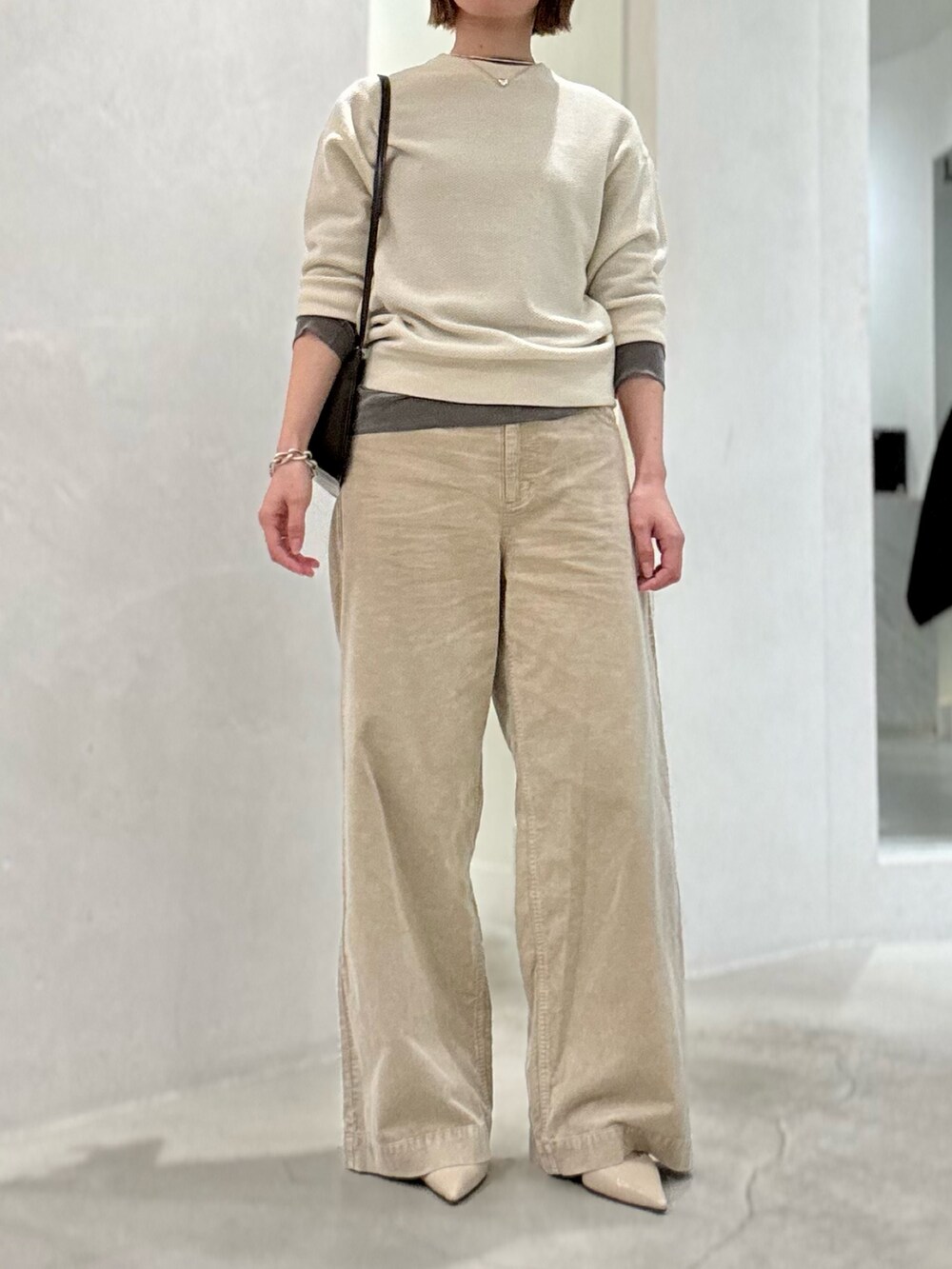 ホワイト系のニット/セーター、グレー系のTシャツ/カットソー、ブラウン系のショルダーバッグを着用したレディースの夏コーディネートの2枚目の写真