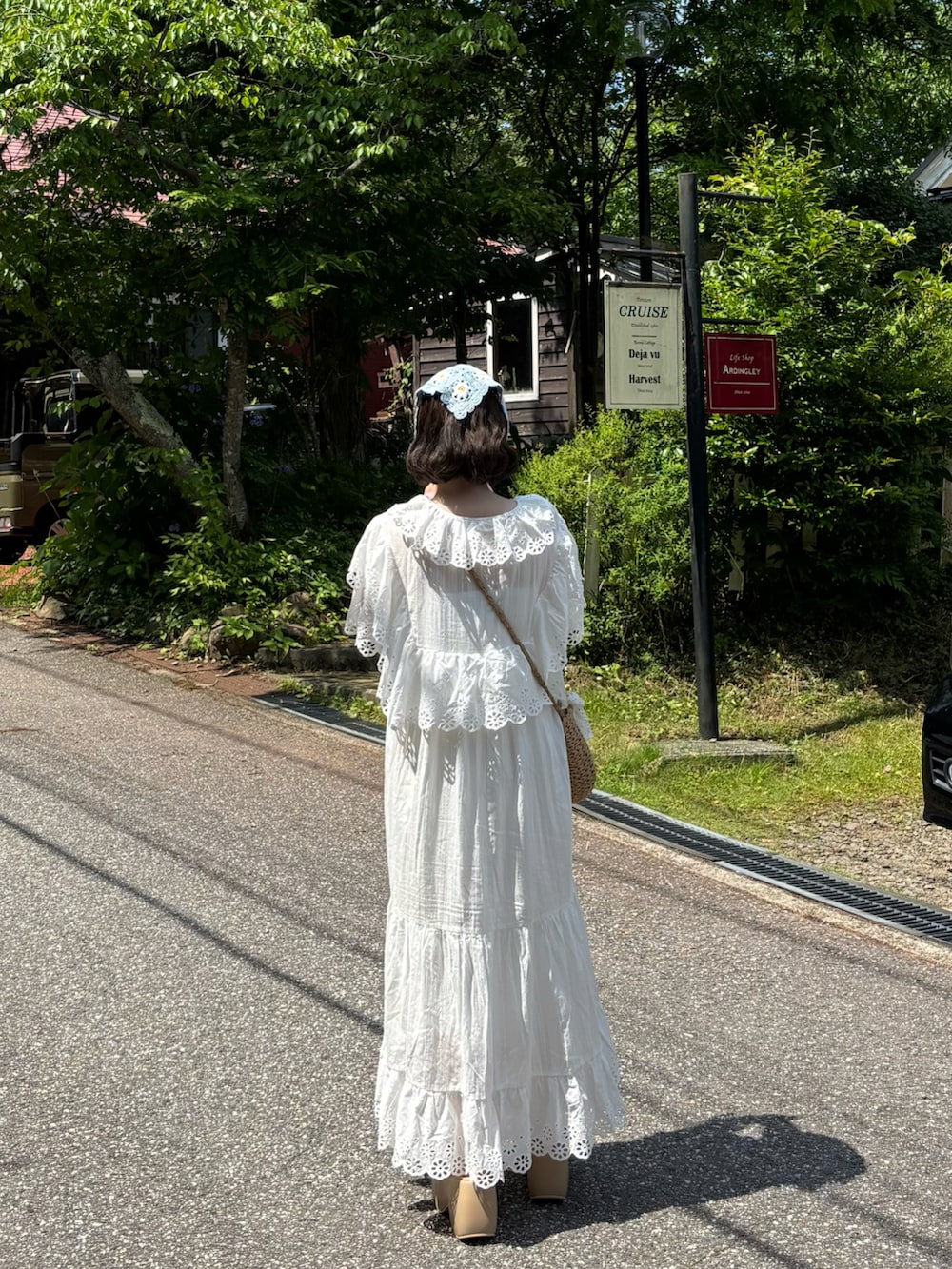 ホワイト系のワンピース、ベージュ系のバッグ、ベージュ系のサンダルを着用したレディースの夏コーディネートの3枚目の写真