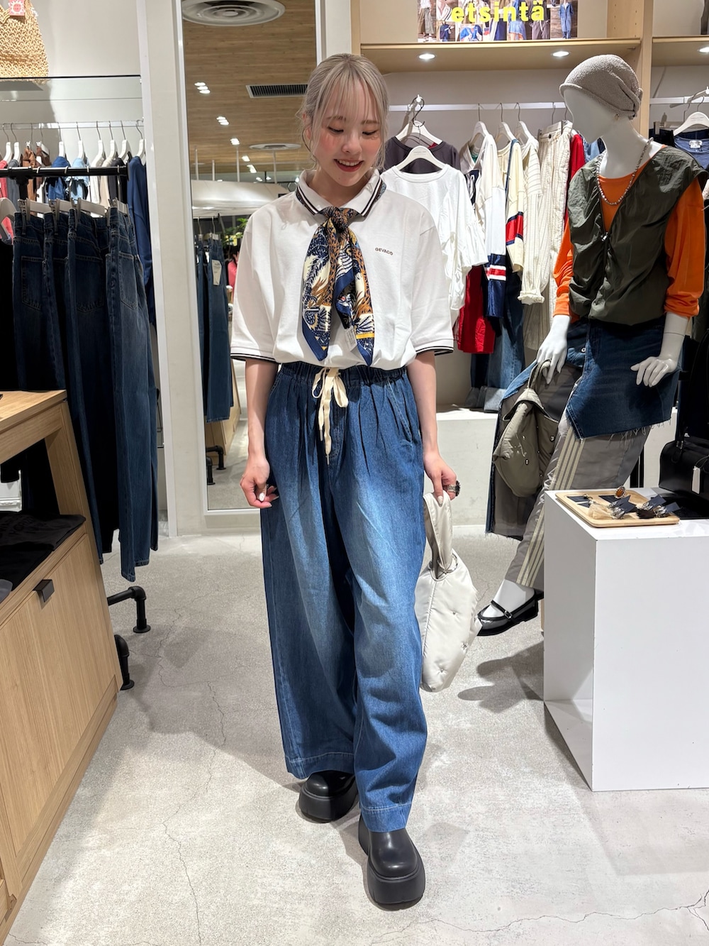 ホワイト系のポロシャツ、ブルー系のデニムパンツ、ブラック系のブーツを着用したレディースの夏コーディネートの4枚目の写真