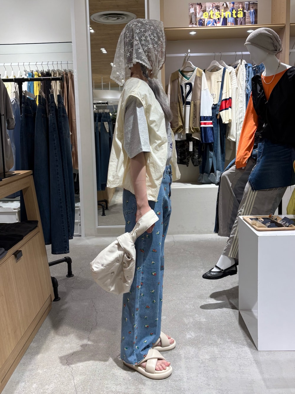 ホワイト系のベスト、グレー系のTシャツ/カットソー、ブルー系のデニムパンツを着用したレディースの夏コーディネートの4枚目の写真