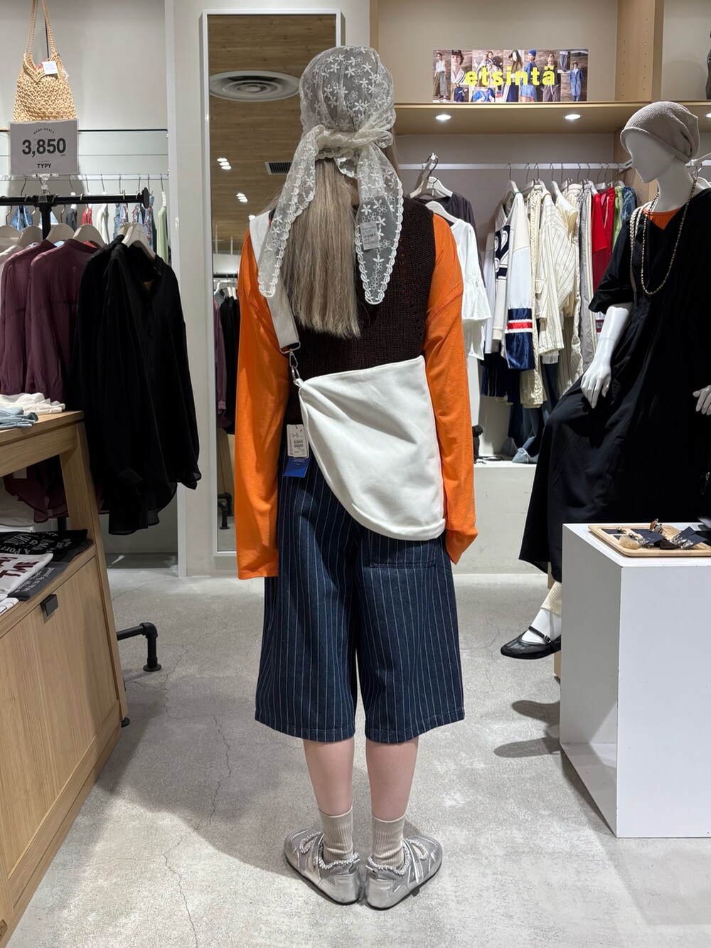 オレンジ系のTシャツ/カットソー、ブラウン系のベスト、ホワイト系のショルダーバッグを着用したレディースの夏コーディネートの3枚目の写真