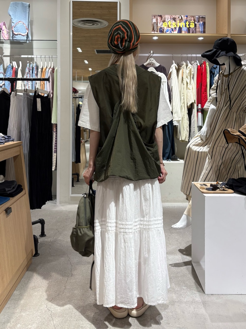 グリーン系のベスト、ホワイト系のTシャツ/カットソー、グリーン系のバックパック/リュックを着用したレディースの夏コーディネートの3枚目の写真