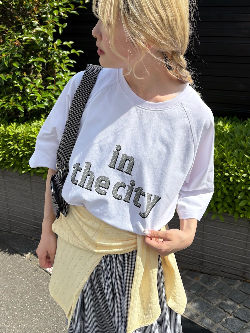ホワイト系のTシャツ/カットソー、イエロー系のTシャツ/カットソー、ブラック系のスカートを着用したレディースの春コーディネートの2枚目の写真
