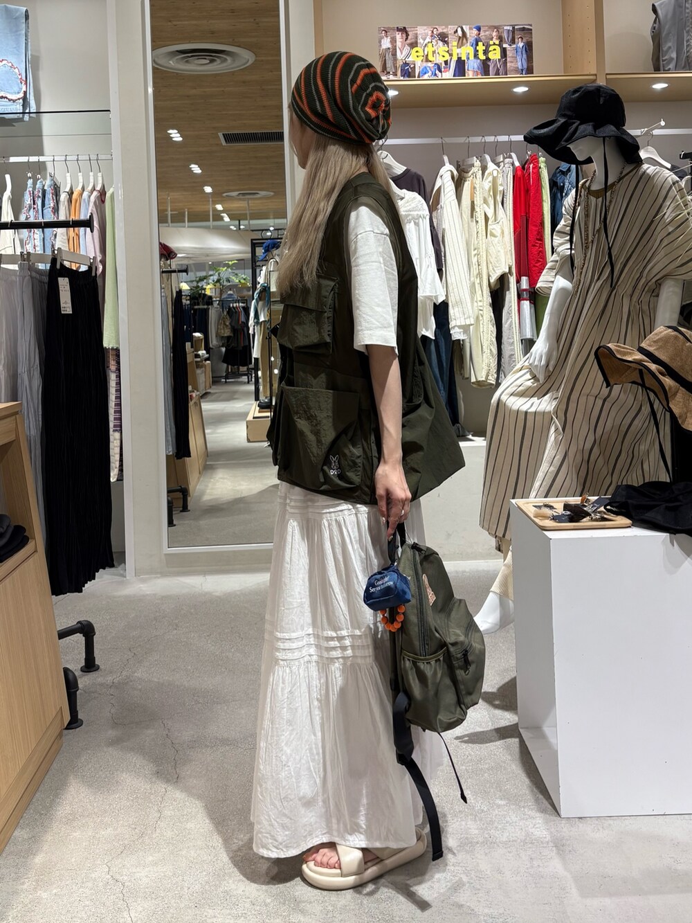 グリーン系のベスト、ホワイト系のTシャツ/カットソー、グリーン系のバックパック/リュックを着用したレディースの夏コーディネートの2枚目の写真